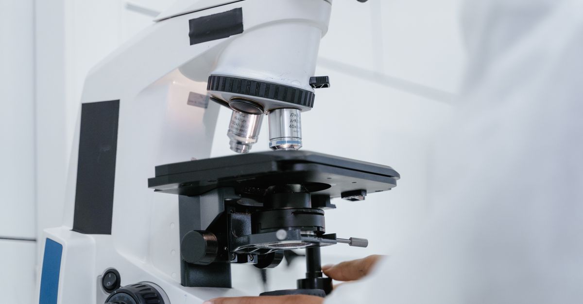 Detailed view of a scientist operating a microscope in a laboratory setting.